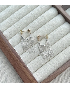 Détail de boucles d'oreilles pampilles en argent avec perles dorées sur lin