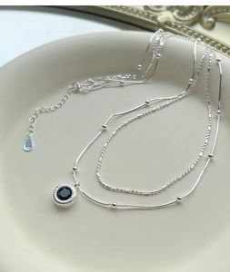 Detailed close-up of double-layer S925 silver necklace with round black onyx pendant