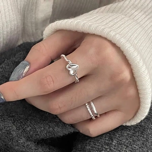 Detail of silver S925 double-layer chain and heart ring worn on a female finger