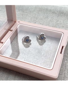 Détail de boucles d'oreilles cœur en argent S925 avec pierre bleue et texture verticale