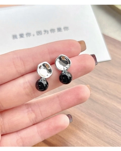 Macro view of silver S925 stud earring featuring irregular concave metal and black agate bead