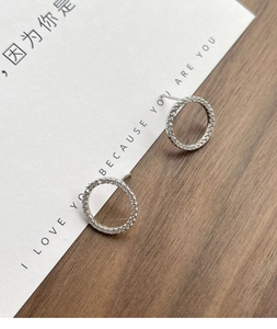 Macro shot of S925 sterling silver hoop earrings with pave cubic zirconia on wood background