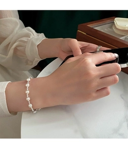 Detailed close-up of S925 silver pearl bracelet with lobster clasp on model's wrist