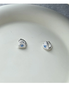 Détail de boucles d'oreilles cœur en argent S925 avec texture et pierre bleue