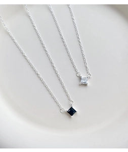 Macro detail of square zircon necklaces with four-prong settings in black and white
