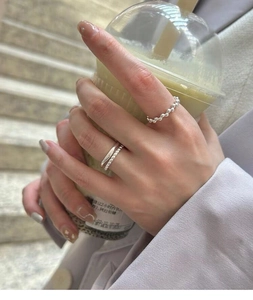 Detail of layered S925 silver rings with beaded and twisted chain textures on hand