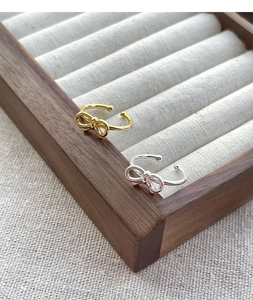 Detailed view of silver and gold bow rings displayed in a velvet jewelry box slot