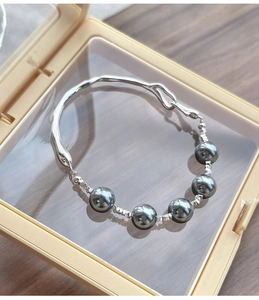 Detail view of five dark pearls on a natural organic fluid S925 silver bracelet design