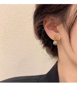 Detail of silver knot earring with a grey pearl on model wearing a black blazer