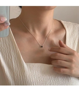 Detail showing a 925 silver necklace with a minimalist black square zircon on collarbone