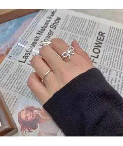 Close-up of S925 sterling silver bow ring and minimalist band on vintage background