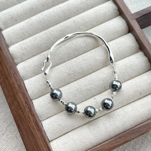Elegant S925 sterling silver wave bracelet featuring five dark grey pearls on linen base