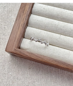 Macro shot of S925 sterling silver twisted braided ring on a natural linen tray