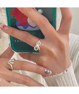 Detailed view of S925 sterling silver bow and snake rings on hand for minimalist style