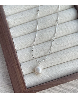Détail d'un collier en argent S925 avec pendentif perle et chaîne serpent à billes