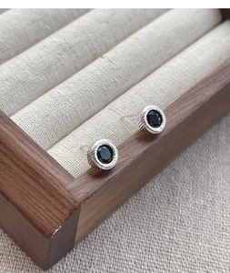 Close-up of S925 sterling silver studs with round black onyx and braided texture finish