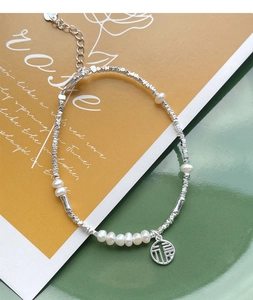 Macro detail of S925 silver bracelet with pearls, silver beads and Fu character charm