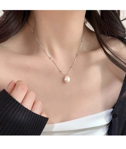 Détail d'une perle blanche ronde sur collier en argent élégant porté par un mannequin