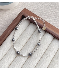 Detailed macro view of S925 sterling silver beads and dark grey pearls with heart charm