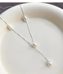 Macro detail of S925 silver Y-shape necklace with four elegant white freshwater pearls