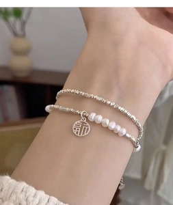 Detail of S925 silver pearl bracelet with a round Fu character lucky charm pendant