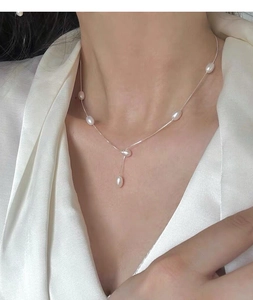 Detail of S925 silver necklace with freshwater pearls on elegant silk shirt fabric