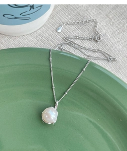 Detail of S925 sterling silver chain with a white freshwater pearl on a ceramic plate