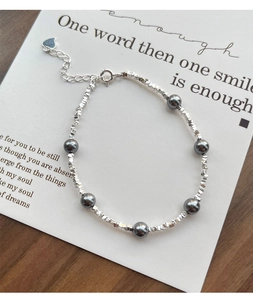 Detail of silver beads and dark grey pearls bracelet with a heart-shaped charm and clasp