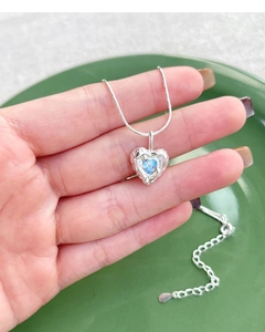 Detail of S925 silver necklace featuring a blue heart zircon in a lava texture frame