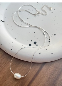 Dettaglio di una collana in argento S925 con perla su vassoio in ceramica e catena