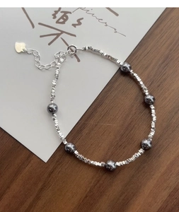 Macro detail of S925 sterling silver beaded bracelet with dark pearls and heart charm