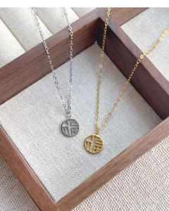 Close-up of gold and silver S925 Fu character pendants on a wooden jewelry display tray