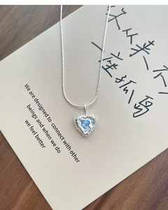 Macro detail of S925 silver heart necklace with blue zircon and irregular texture