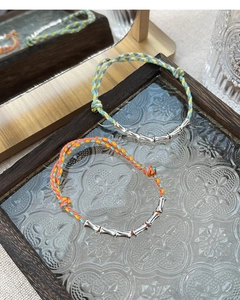Close-up of handmade woven rope bracelet with S925 silver bamboo joints on glass tray