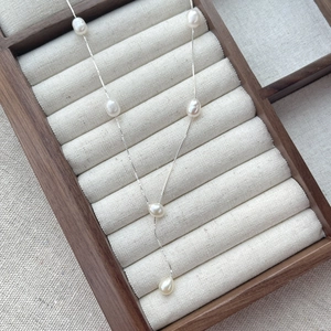 Elegant S925 sterling silver necklace featuring six freshwater pearls on a walnut display