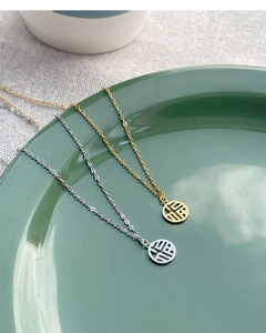Close-up of S925 silver Fu character pendant necklace on green ceramic plate