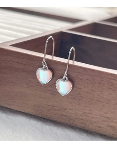 Primer plano de aretes de corazón de plata S925 con piedra de luna y bordes perlados finos