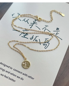 Detail of S925 sterling silver gold-plated Fu pendant on literary book background