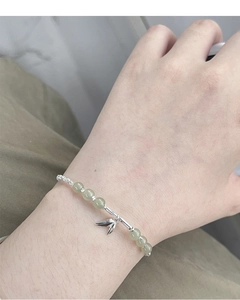 Detail showing S925 silver bamboo leaf charm and green jade beads on woman's wrist