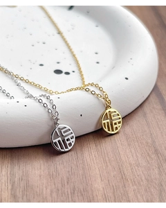 Macro view of gold and silver S925 sterling silver Fu character pendants on fine chains