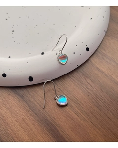 Primer plano de aretes de corazón de plata S925 con piedra de luna iridiscente