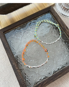 Detail of colorful braided S925 silver bamboo bracelet on vintage glass frame