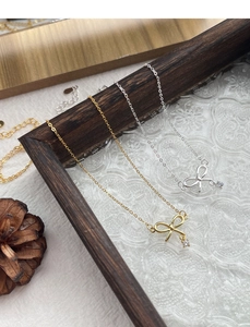 Détails de pendentifs nœuds en argent et or avec zircons sur cadre vintage