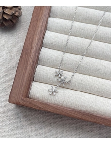 Detail of silver S925 snowflake pendant with zircons on a beige jewelry display tray