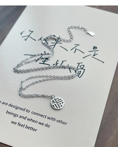 Macro shot of S925 sterling silver Fu pendant necklace on a beige display card