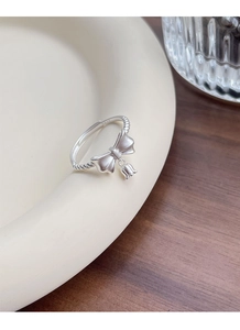 Macro shot of S925 sterling silver bow ring with lily of the valley charm on a ceramic plate