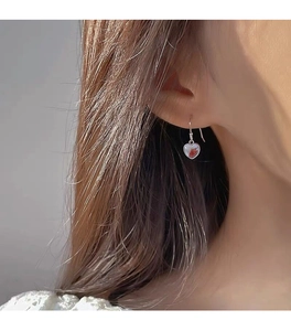 Primer plano de pendiente de corazón en plata S925 con piedra lunar usado por modelo