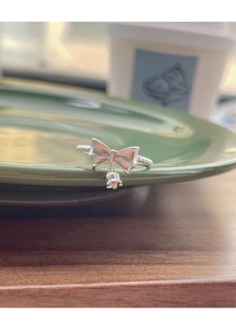 Detailed macro view of S925 silver bow ring with dangling lily of the valley charm