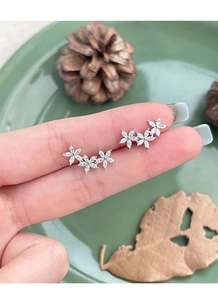 Detail of silver five-petal flower stud earrings with sparkling cubic zirconia stones