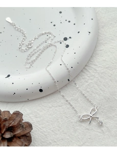 Détail du collier noeud en argent S925 avec zircon sur un plateau en céramique blanche